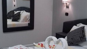 A hotel room with a bed, a large mirror, and a wall-mounted light fixture. - le pinède vistamare (Pozzuoli)