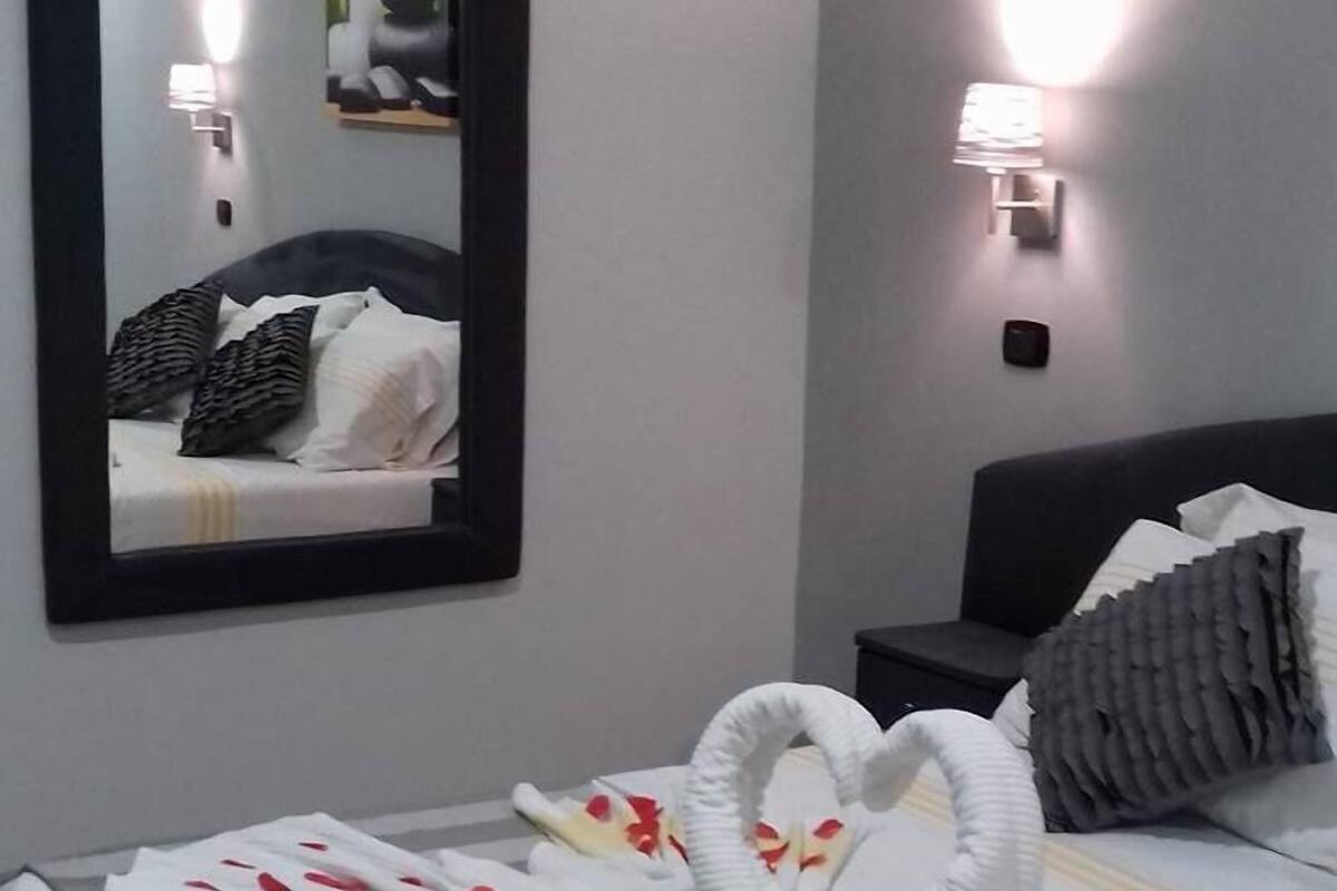 A hotel room with a bed, a large mirror, and a wall-mounted light fixture.