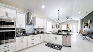 A modern kitchen with white cabinetry, stainless steel appliances, and a black countertop.
