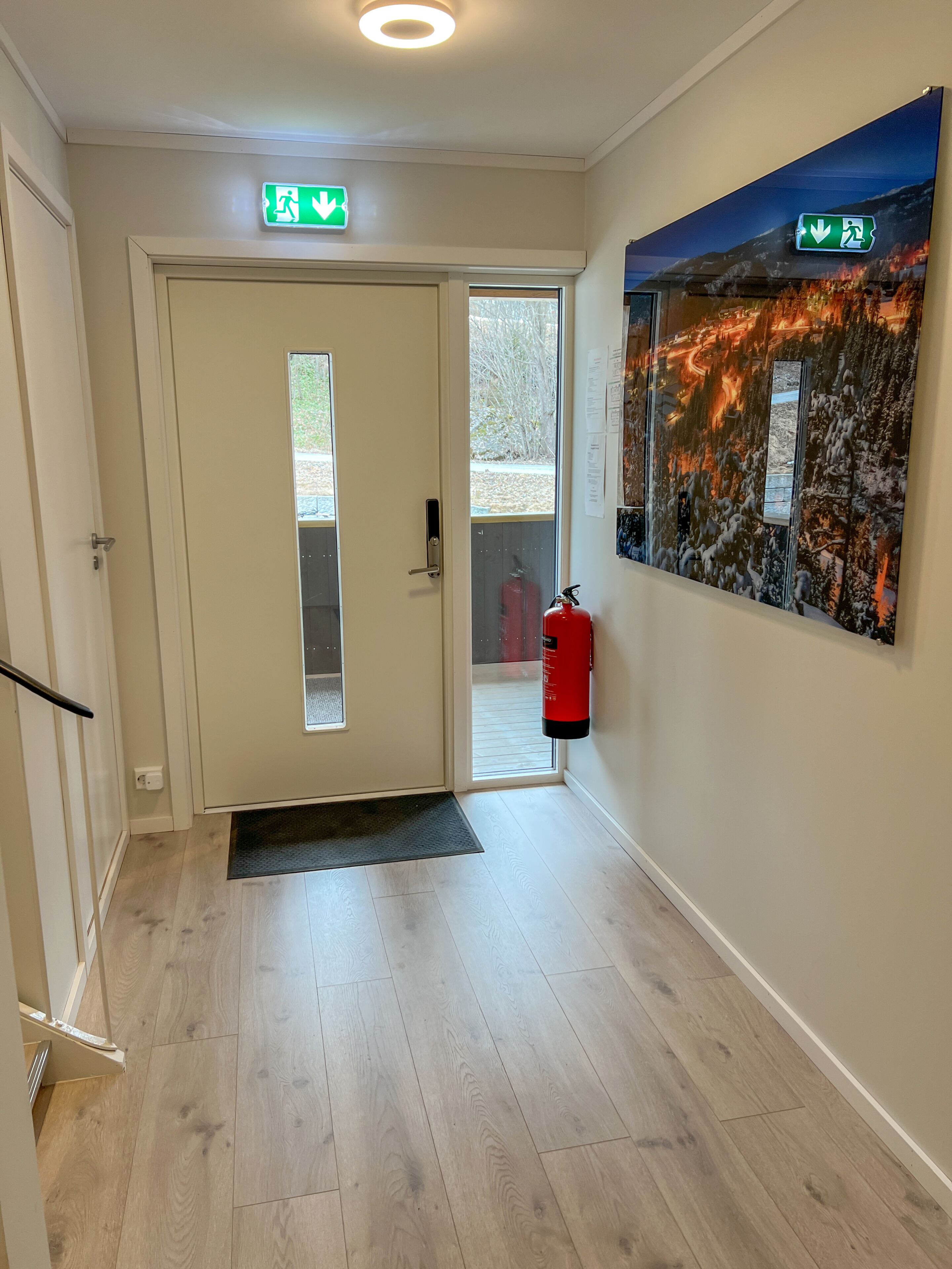 Ein Flur mit einer Tür, einem Feuerlöscher und einem an der Wand befestigten Schild.