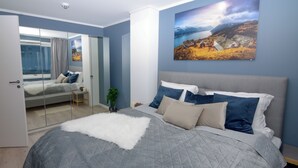 A bedroom with a bed, a mirror, a window, and a painting on the wall. - Haugetuft Apartments  (Vinje)