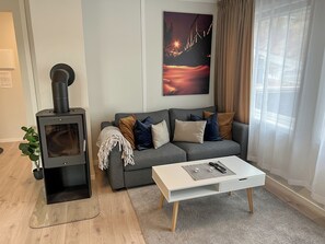 Ein Wohnzimmer mit einer Couch, einem weißen Couchtisch, einem Kamin und einem Gemälde an der Wand.