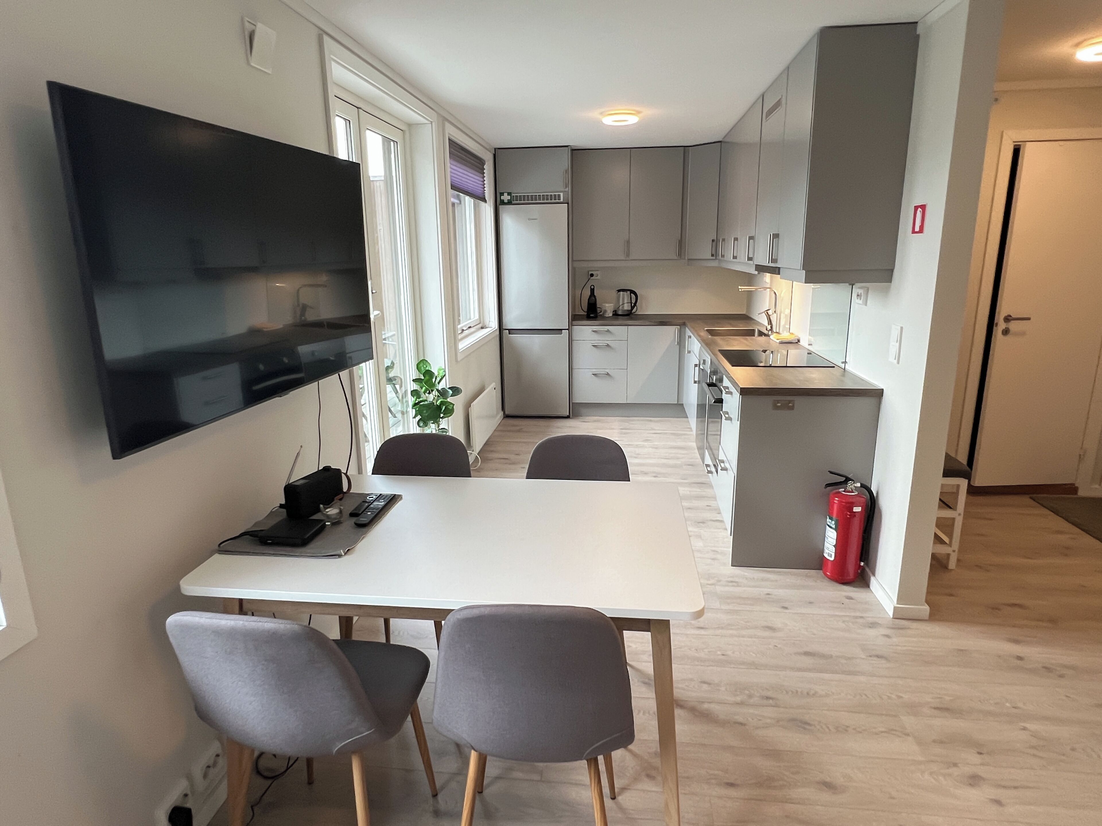 Una cocina moderna con comedor, electrodomésticos integrados y un televisor de pantalla plana.