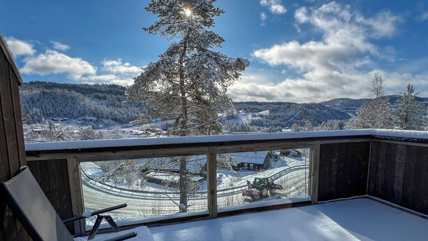A snow-covered balcony with a view of a snowy landscape, a chair, and a wooden structure. - Haugetuft Apartments  (Vinje)