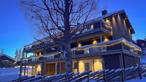 A multi-story building with balconies, snow-covered ground, and string lights. - Haugetuft Apartments  (Vinje)