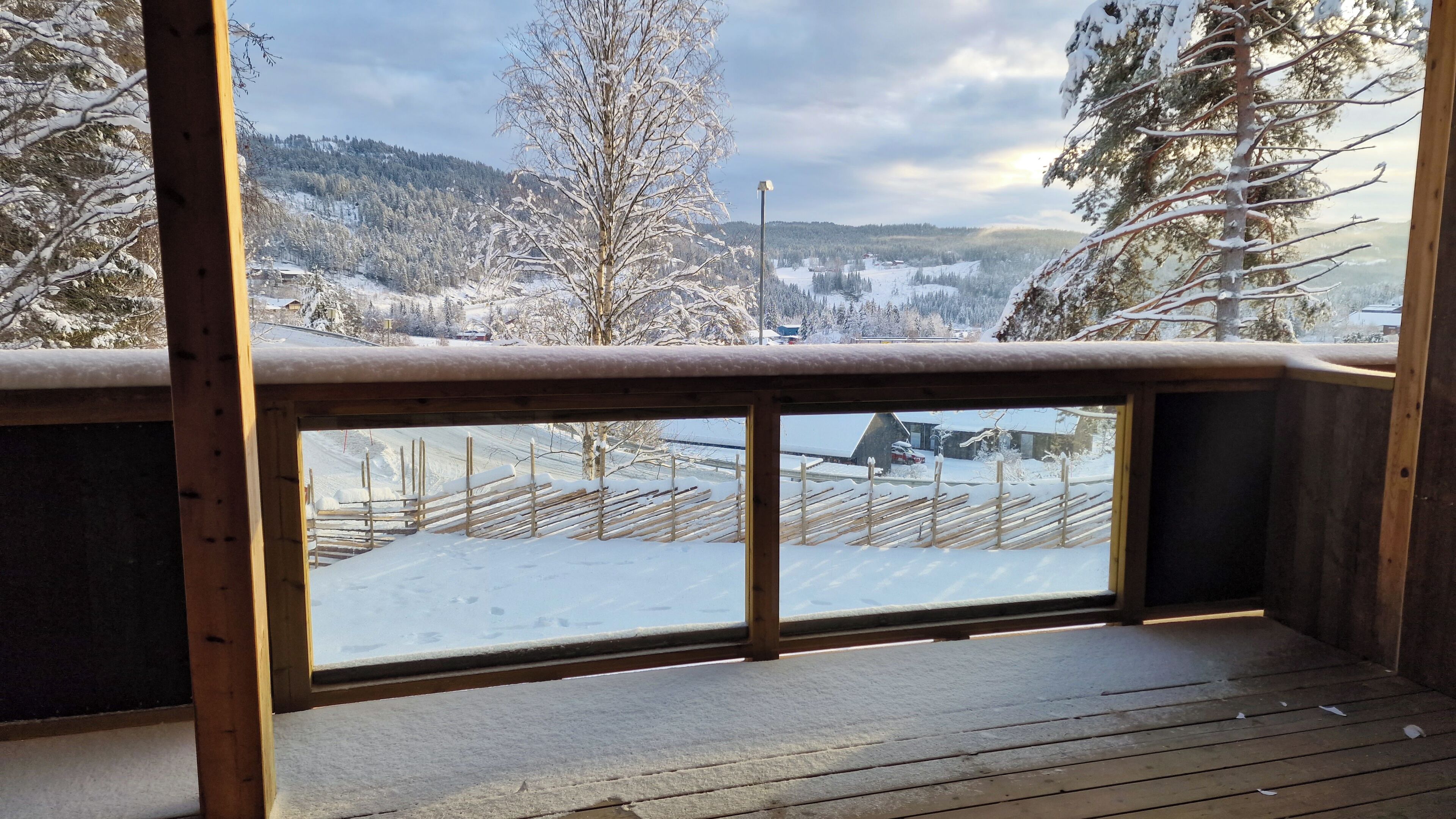 A wooden deck with a view of a snowy landscape and a wooden fence.