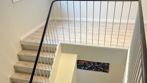 A staircase with a metal handrail, wooden steps, and a picture frame on the wall. - Haugetuft Apartments  (Vinje)
