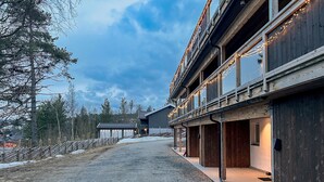 A building with a gravel driveway, wooden exterior, and multiple windows. - Haugetuft Apartments  (Vinje)