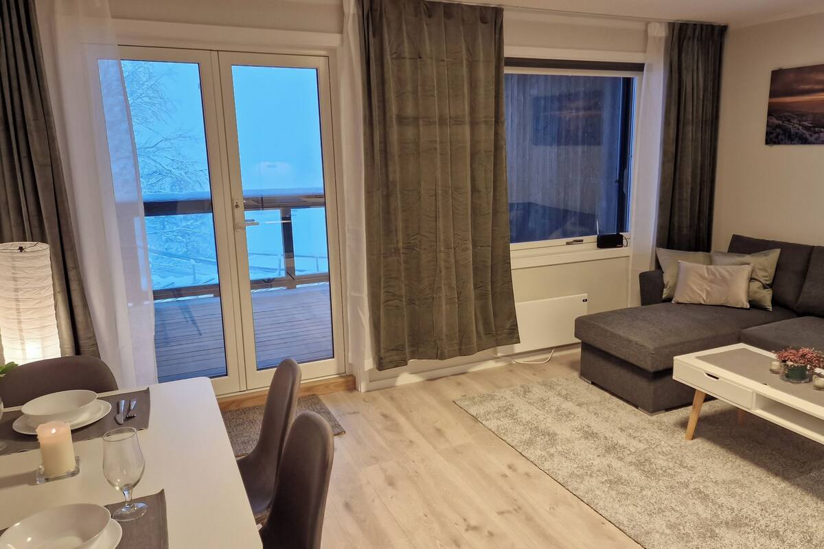 Ett modernt vardagsrum med en soffa, ett soffbord och en matplats med ett ljus.