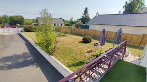 A residential backyard with a paved driveway, a lawn, and a metal fence. - Detached house near SAINT MALO (Miniac-Morvan)