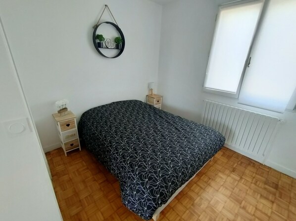 Een slaapkamer met een bed, nachtkastje, radiator en raam.