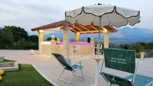 Eine Außenpatio mit Barbereich, grüner Rasenfläche und Bergblick.