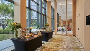 Un hall d’hôtel spacieux, doté de grandes fenêtres, d’un tapis à motifs et d’un comptoir d’accueil situé au fond.
