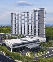 Un hotel moderno con una estructura de varios pisos, entrada cubierta y un área ajardinada con árboles y una carretera curva.