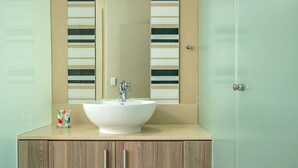 A bathroom with a white sink, a mirror, and wooden cabinets. - The Tyrwhitt Unit 408 (Johannesburg)