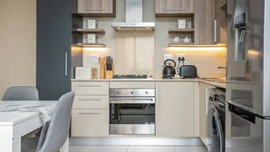A modern kitchen with wooden cabinets, a built-in oven, a dishwasher, and a refrigerator. - The Tyrwhitt Unit 408 (Johannesburg)