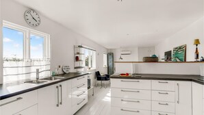 Een moderne keuken met witte kasten, een zwart aanrecht, een klok en uitzicht op de omgeving.