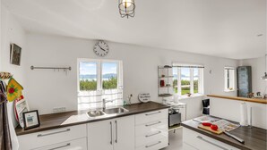 Een moderne keuken met witte kasten, een roestvrijstalen spoelbak en een raam met uitzicht op een schilderachtig landschap.