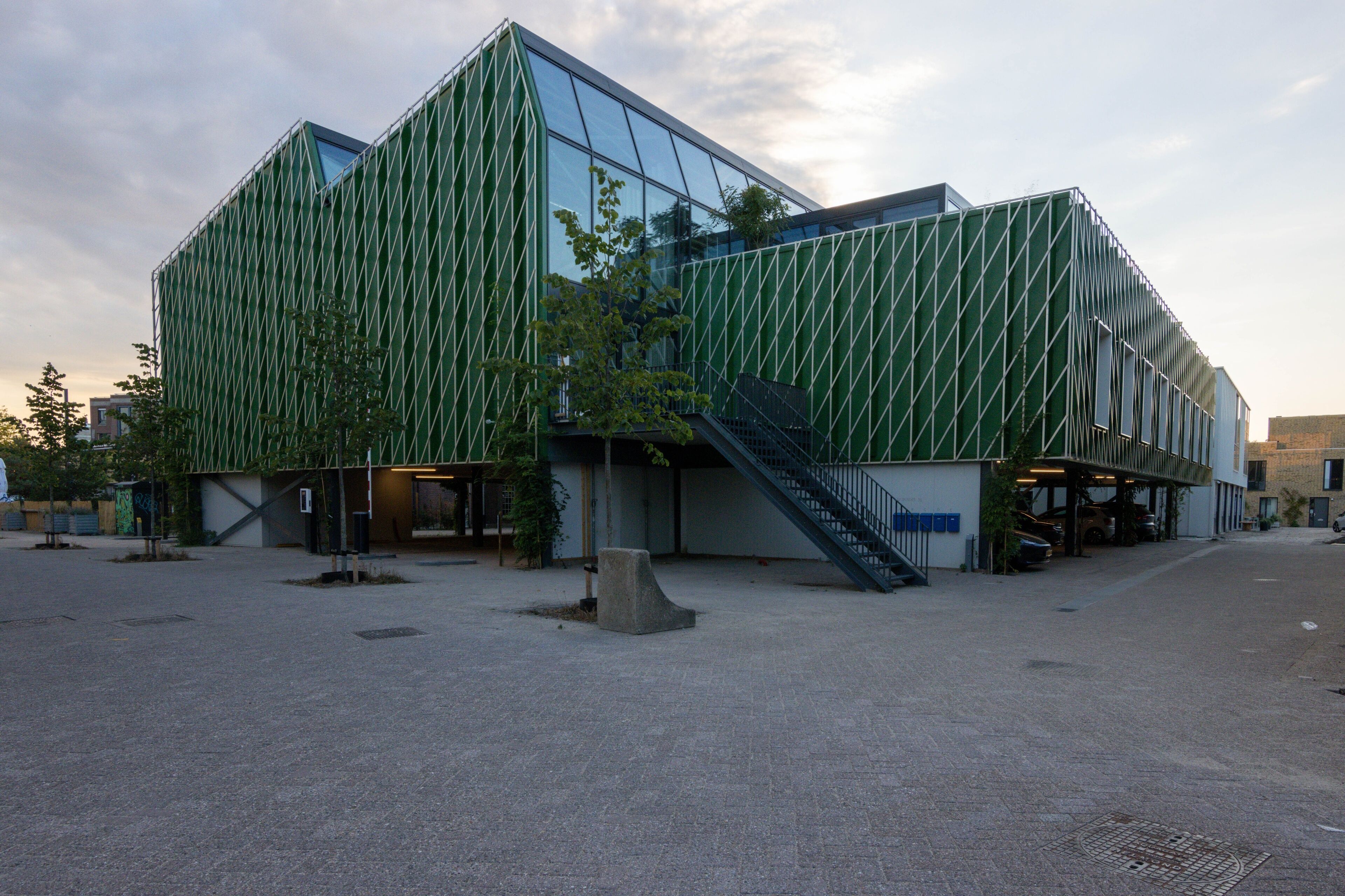 En modern byggnad med en grön fasad och stora fönster.
