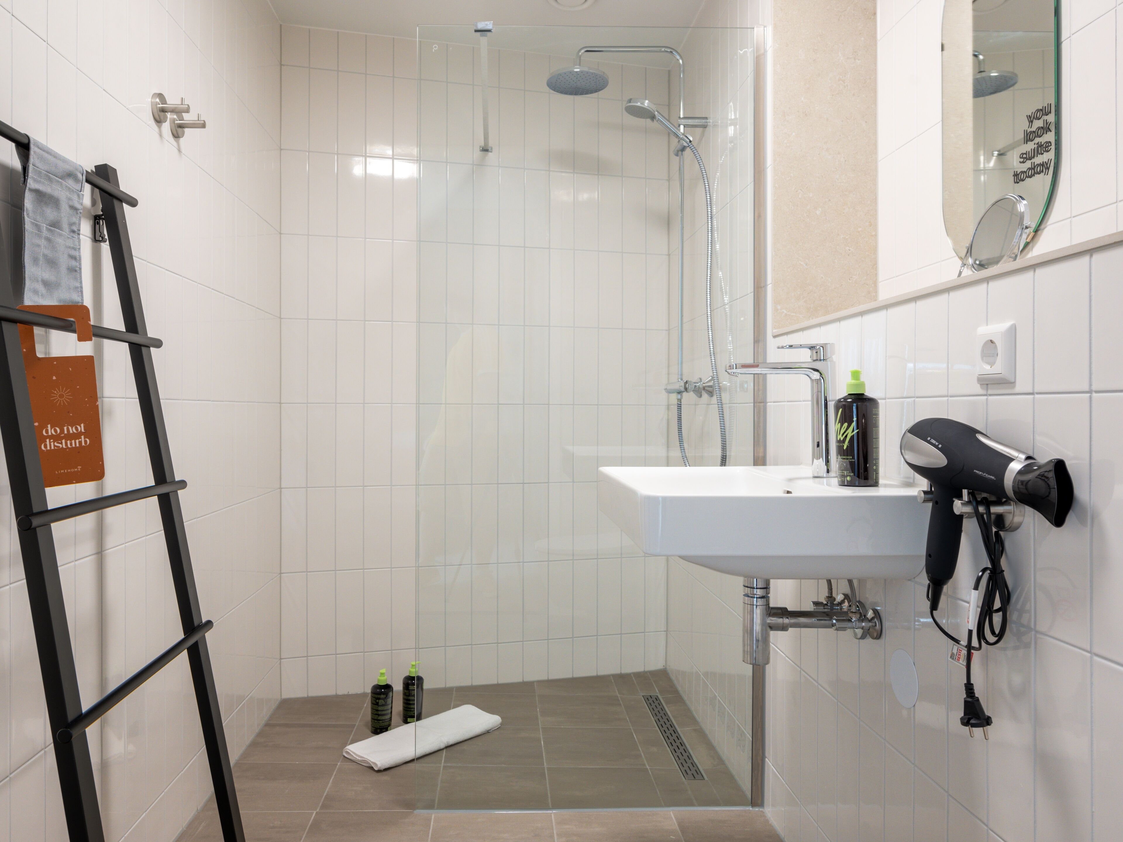 A modern bathroom with a shower, sink, and hairdryer.