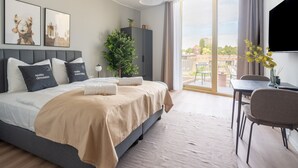 Une chambre d’hôtel moderne, dotée d’un grand lit, d’un bureau, d’une chaise, d’une plante en pot et offrant une vue sur la ville.