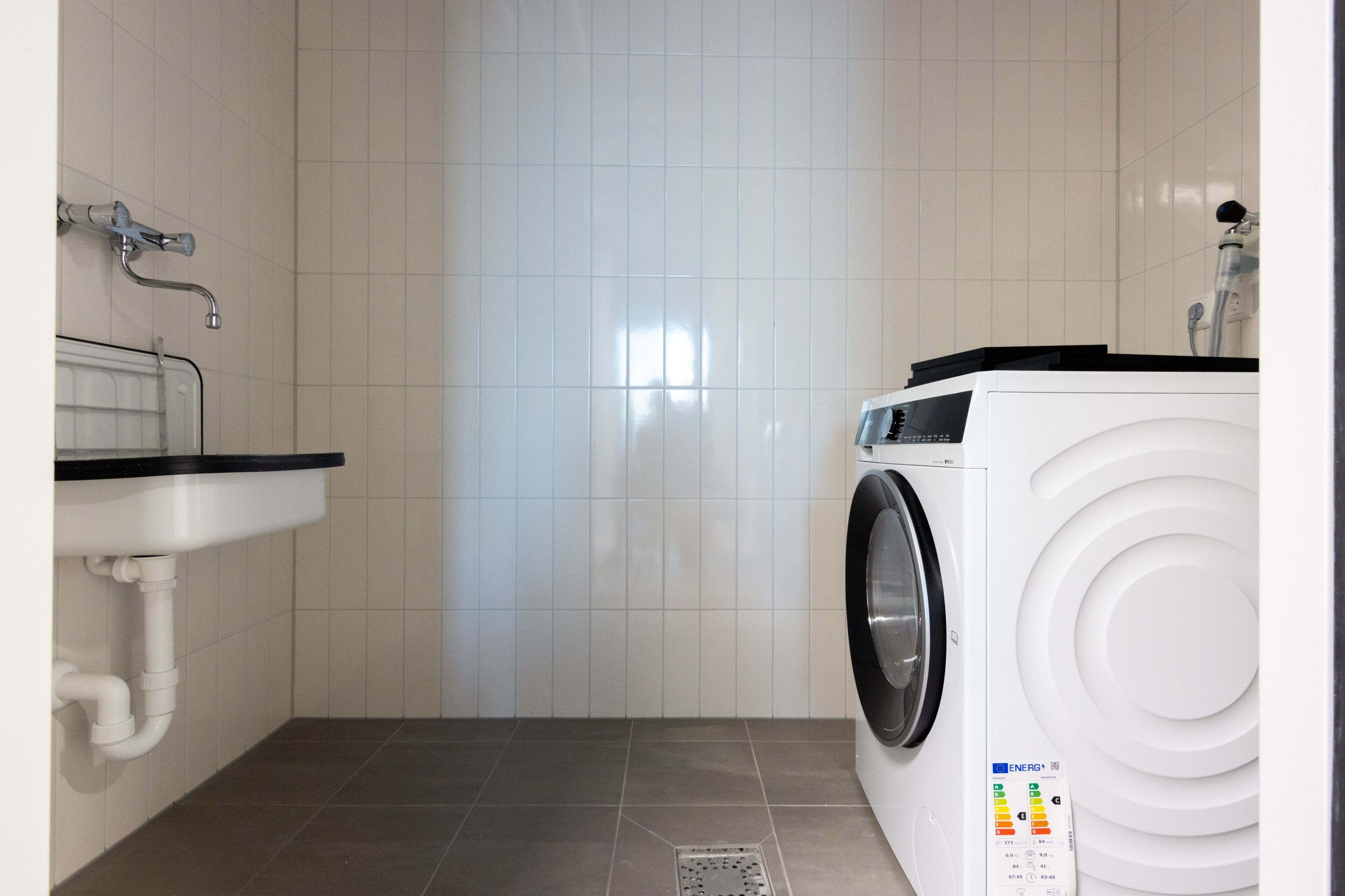 Un cuarto de lavado con lavadora, un lavabo y una ducha.