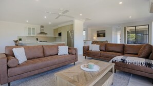 A modern living room with two brown leather sofas, a wooden coffee table, and a ceiling fan.