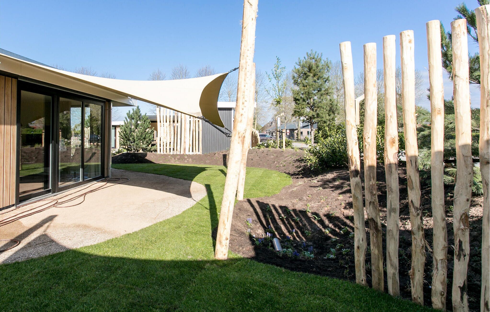 Une maison moderne dotée de grandes fenêtres en verre, d’un toit incurvé et d’une clôture en bois.