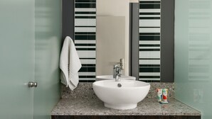 Ein Badezimmer mit einem weißen Waschbecken, einem Handtuch, das an der Tür hängt, und einem Spiegel mit vertikalen Streifen.