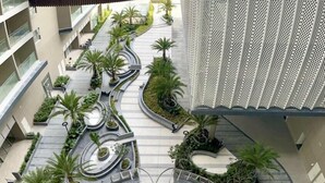 A modern building with a central courtyard featuring a circular design, surrounded by palm trees and a walkway.