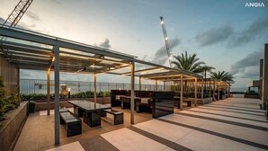 A rooftop terrace with outdoor seating, a covered area, and a view of the sea.