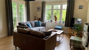 A living room with a brown sofa, a coffee table, a television, and a window with curtains.