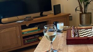 A living room with a TV, a glass of wine, a chessboard, and a bookshelf.