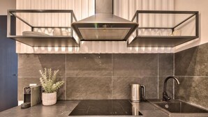 Una cocina moderna con extractor de humos empotrado, un lavamanos de acero inoxidable y una planta en maceta.