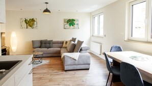 A modern living room with a grey sofa, a dining table with chairs, and a kitchen area. - Fewo für die Familie Dachterrasse Trocker/waschmaschine Netflix Jarody (Senheim (Mosel))