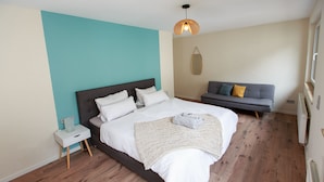 A bedroom with a bed, a bedside table, a grey sofa, and a hanging light fixture. - Fewo für die Familie Dachterrasse Trocker/waschmaschine Netflix Jarody (Senheim (Mosel))
