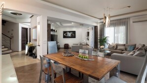 Ein modernes Wohnzimmer mit einem Holzesstisch, einer Couch und einer Küchenzeile im Hintergrund.
