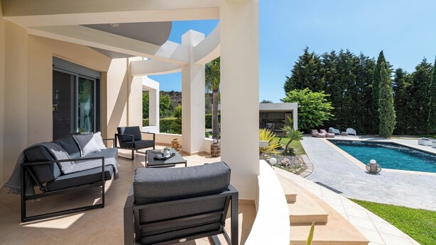 Ein moderner Außenbereich mit Pool, Sitzgelegenheiten und Blick auf die umliegende Landschaft.
