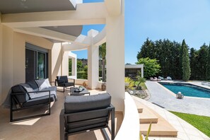 A modern outdoor living area with a pool, seating, and a view of the surrounding landscape.