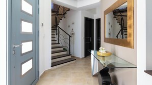 Ein modernes Interieur mit Treppe, einem Glastisch und einer blauen Tür.