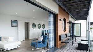 A modern living room with a white sofa, blue armchair, and a dining area with a table and chairs. - This Apartment is No Longer Available (Woolacombe)