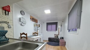 A compact kitchen with a sink, a clock, and a bookshelf. - CHALET DESIGN NATURA JACUZZI GUEST DREAM (Esposende)