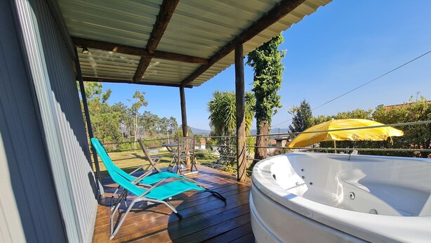 A wooden deck with a hot tub, blue lounge chairs, and a yellow umbrella. - CHALET DESIGN NATURA JACUZZI GUEST DREAM (Esposende)