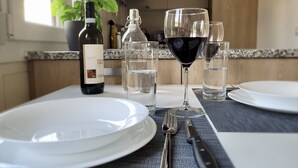 A dining table set with white plates, clear glasses, a wine bottle, and cutlery. - Central and cozy- FREE PARKING (Lugano)