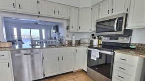 Een moderne keuken met witte kasten, roestvrijstalen apparatuur en uitzicht buiten.