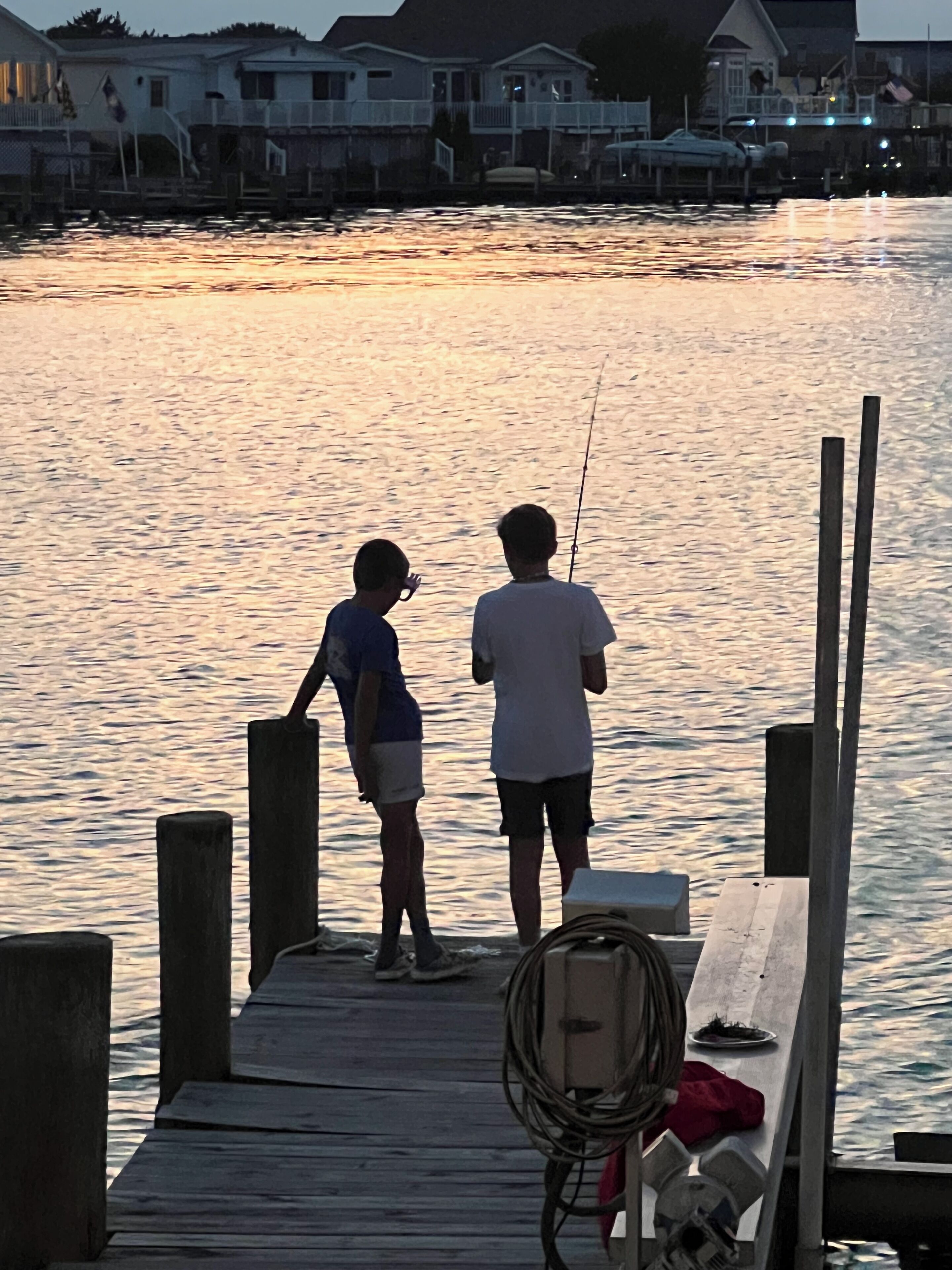 Muelles de madera que se adentran en aguas tranquilas, con dos personas pescando.