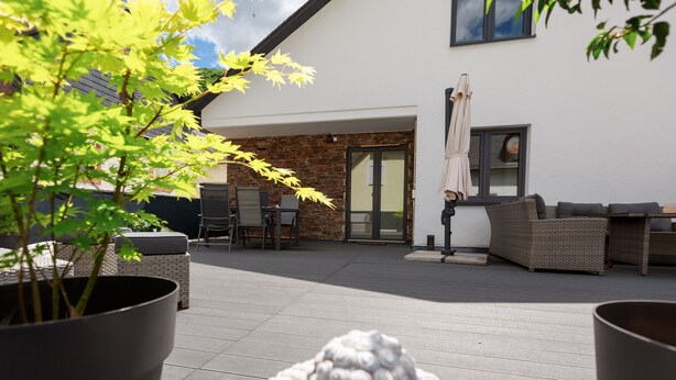 A patio area with outdoor furniture, a potted plant, and a stone wall.