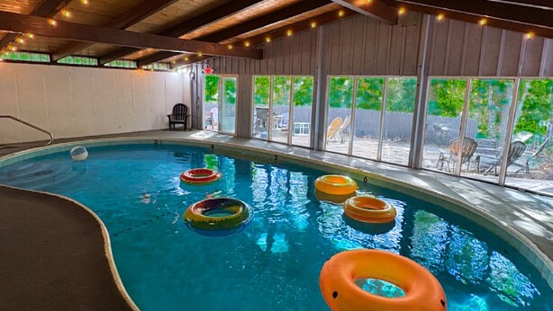 Ein Hallenbad mit Holzbalken, großen Fenstern und schwimmenden Ringen.