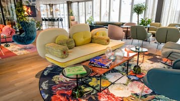 A modern lounge area with a sofa, chairs, a coffee table, and a bookshelf with books.