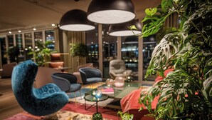 A modern lounge area with a blue armchair, a glass coffee table, and a large potted plant.